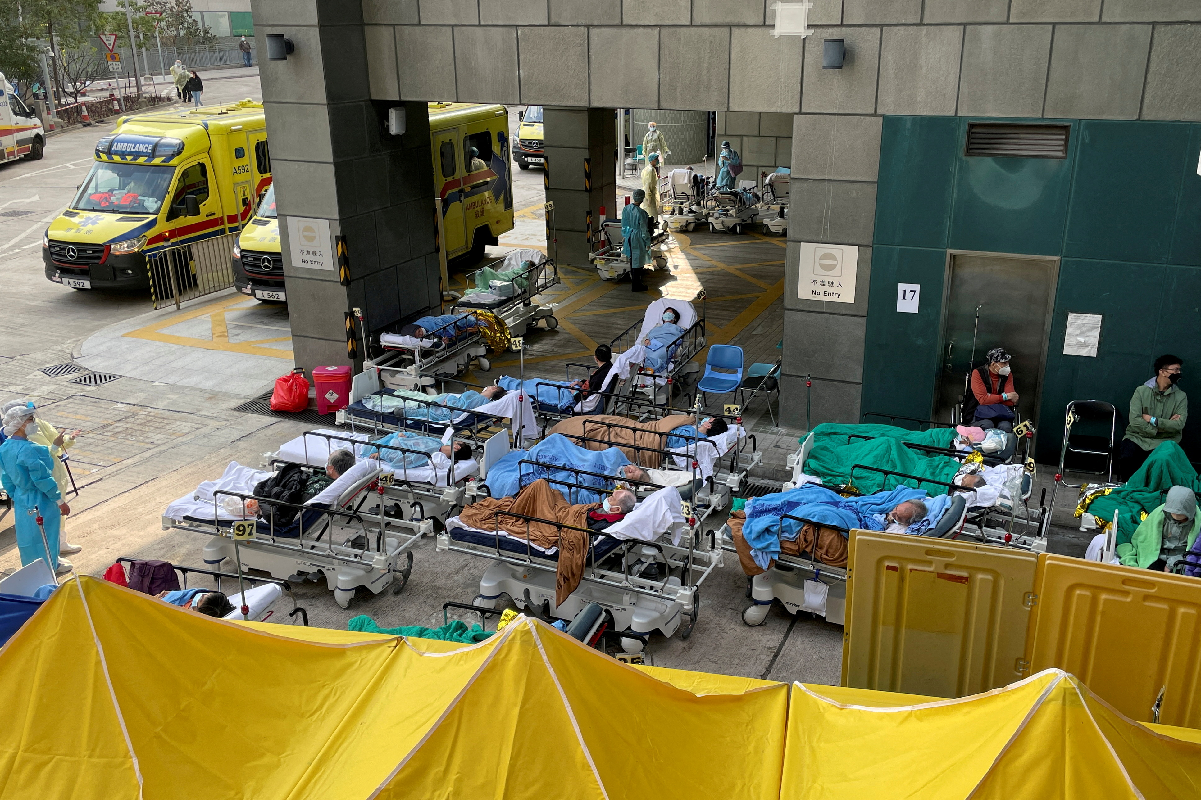 FILE PHOTO: Patients wearing face masks lie in bed at a makeshift treatment area outside a hospital, following the coronavirus disease (COVID-19) outbreak in Hong Kong, China February 16, 2022. REUTERS/Aleksander Solum